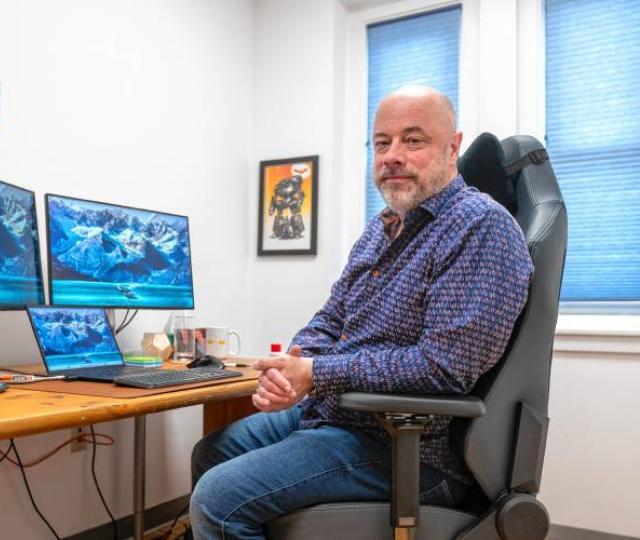 Joe Minton sitting at a desk with multiple screens