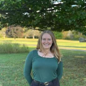 Claire Guillemin wearing a greet top, smiling outdoors