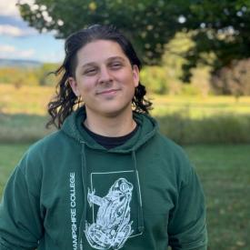 Isaac (Ike) Rubin wearing a green hoodie, smiling outside against a green landscape