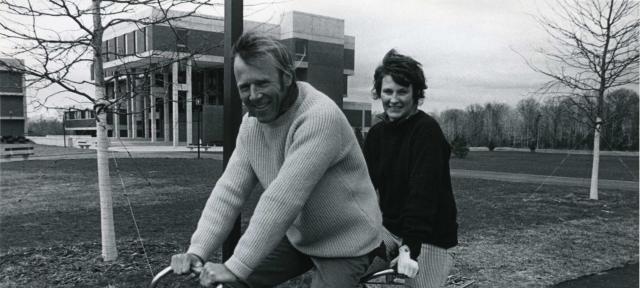 Chuck and Polly Longsworth riding a bike on the Hampshire campus