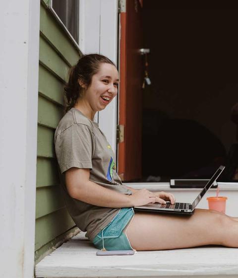 Student sitting outside working on a laptop.