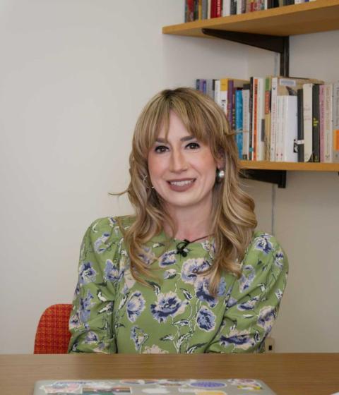 Jina Fast is sitting in her office wearing a green dress.