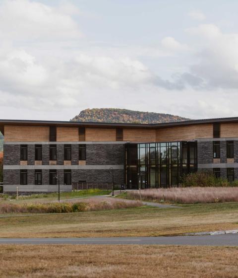 The Kern Building in the fall at dusk. Tones of green and brown with a blue sky in the background.