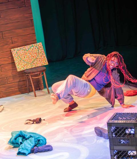 A still photo from one of Hampshire's theatre productions. This colorful photo depicts a student dancing on stage.