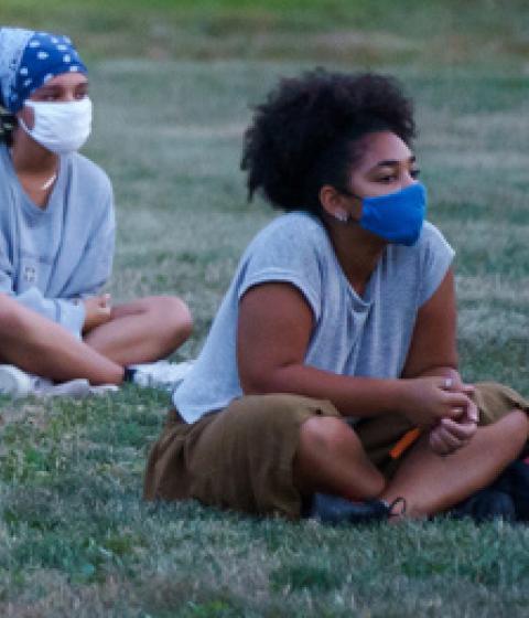 Students with masks sitting outside at new student orientation